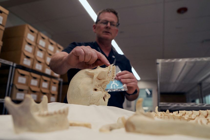 Pima County Chief Medical Examiner Gregory Hess examines the skeletal remains of an unidentified person found in the Arizona desert near the border with Mexico, in Tucson, Arizona.